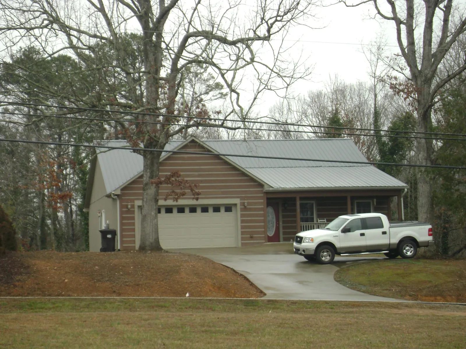 Gray metal roof on a log sided house with an attached two car garage in Spencer